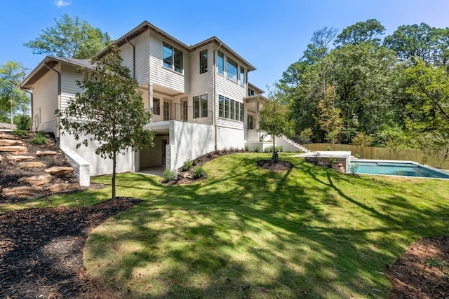 rear view of house featuring a balcony and a lawn