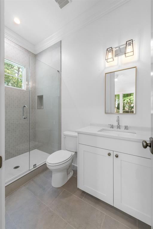 bathroom featuring crown molding, tile patterned floors, toilet, a shower with shower door, and vanity