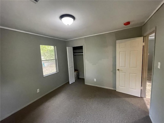 unfurnished bedroom featuring dark colored carpet, ornamental molding, and a closet