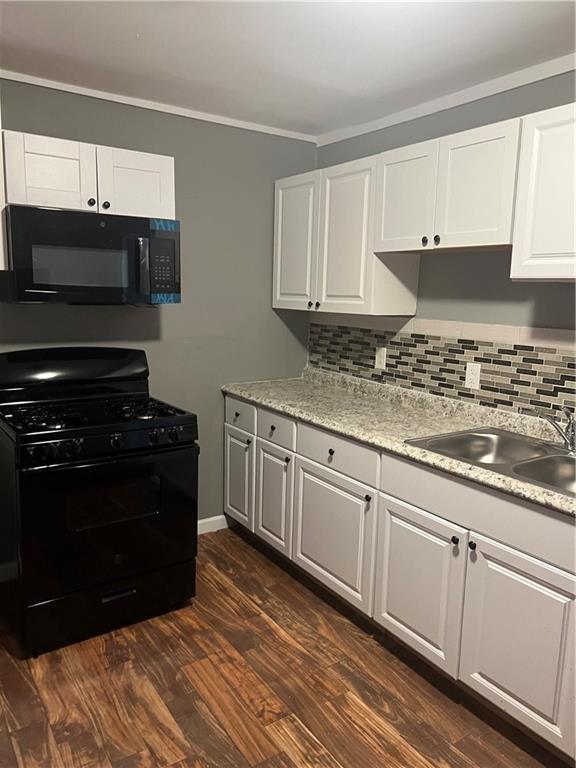 kitchen featuring black appliances, backsplash, white cabinetry, and dark wood-type flooring