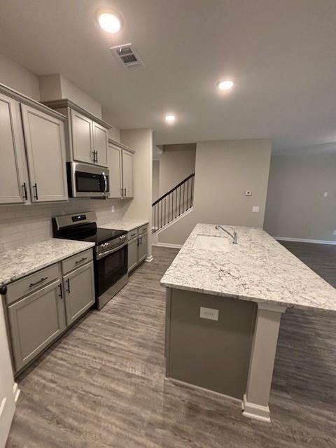 kitchen featuring tasteful backsplash, light stone countertops, and dark brown cabinets