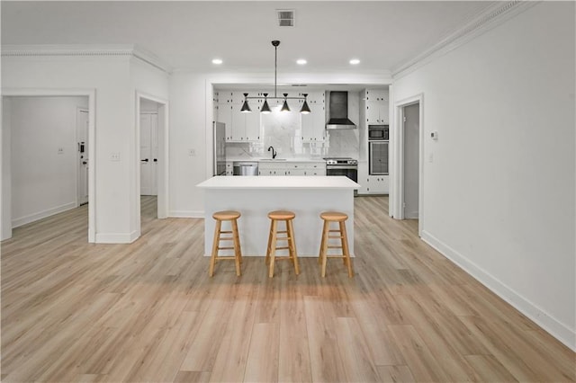 3649 Peachtree Rd NE Unit 305, Atlanta, GA 30319 - kitchen with wall chimney exhaust hood, appliances with stainless steel finishes, a kitchen breakfast bar, light countertops, and white cabinetry