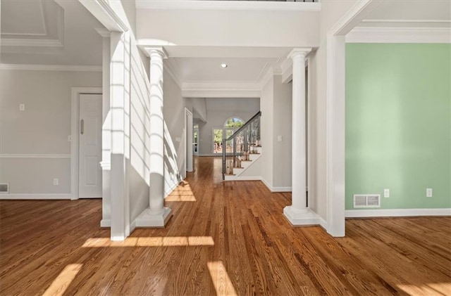 entrance foyer featuring visible vents, crown molding, baseboards, decorative columns, and wood finished floors