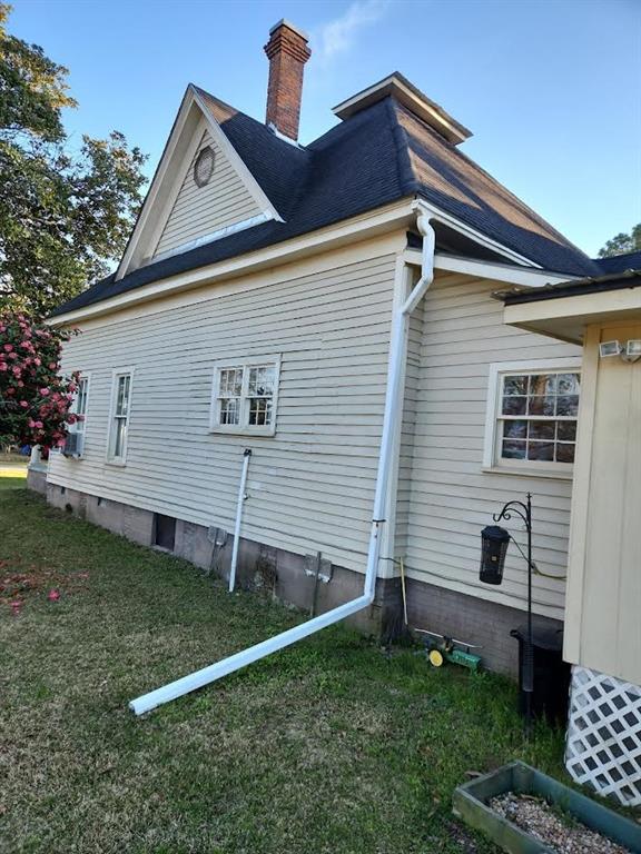 view of side of home featuring a chimney and a yard