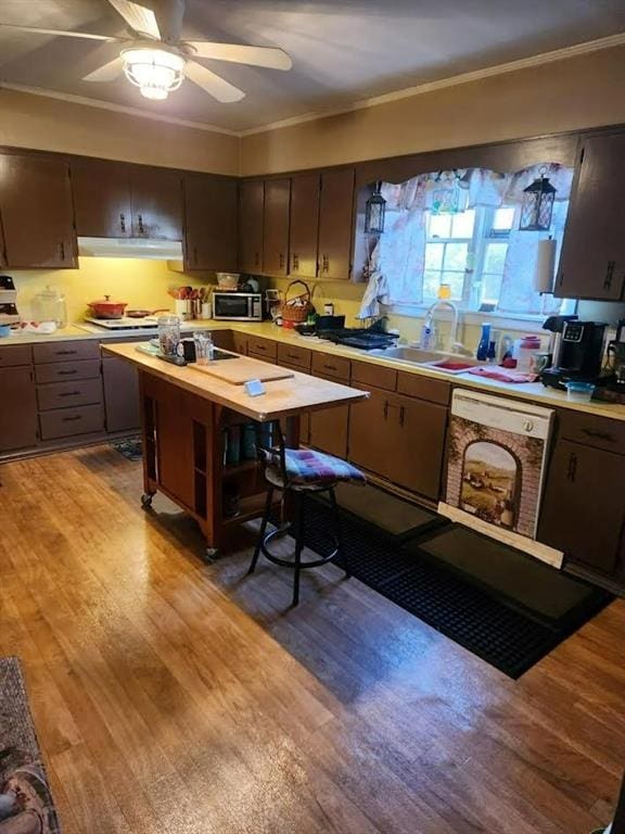 kitchen with stainless steel microwave, light wood-style flooring, ornamental molding, and white dishwasher