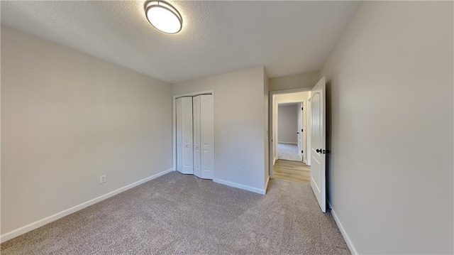 unfurnished bedroom with a textured ceiling, a closet, and light carpet