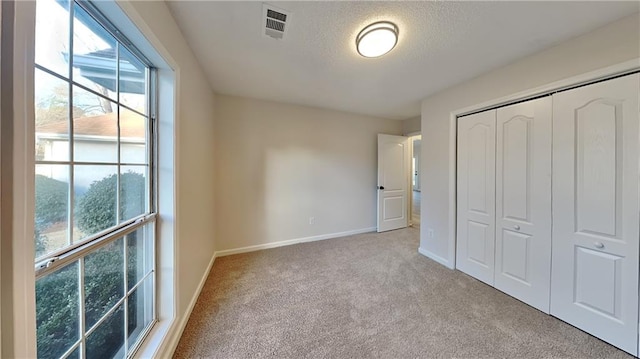 unfurnished bedroom with a textured ceiling, a closet, and light carpet