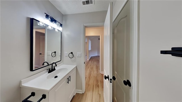 bathroom featuring wood-type flooring, vanity, and a textured ceiling