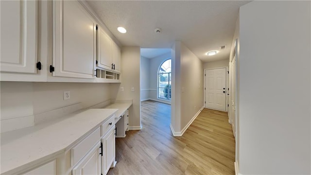 interior space featuring white cabinets, light stone counters, and light hardwood / wood-style flooring