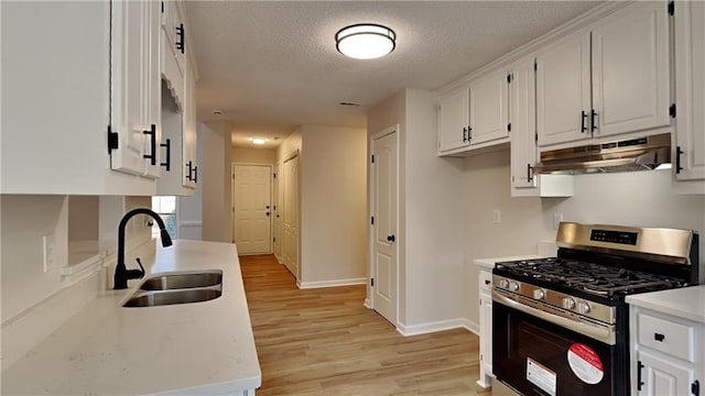 kitchen with sink, white cabinetry, a textured ceiling, and stainless steel gas range oven