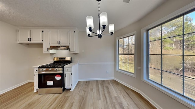 kitchen with an inviting chandelier, stainless steel range with gas stovetop, pendant lighting, and white cabinetry