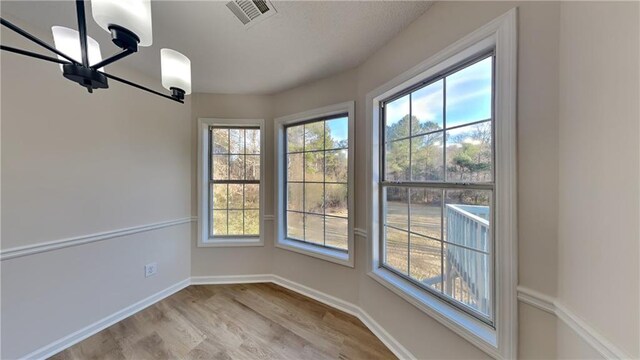 unfurnished dining area with light hardwood / wood-style floors and an inviting chandelier