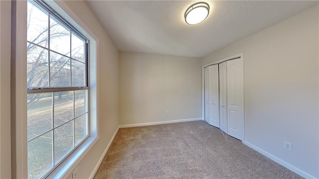 empty room featuring light colored carpet, a textured ceiling, and a healthy amount of sunlight