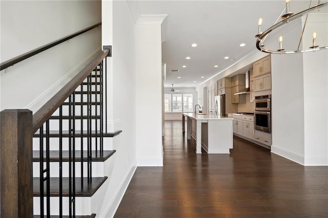 stairs featuring ornamental molding, hardwood / wood-style flooring, and ceiling fan with notable chandelier