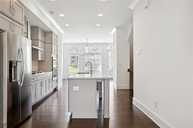 kitchen with appliances with stainless steel finishes, ornamental molding, an island with sink, and dark hardwood / wood-style floors