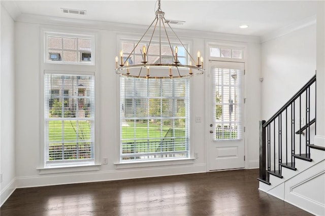 foyer featuring a notable chandelier, dark hardwood / wood-style floors, crown molding, and a wealth of natural light