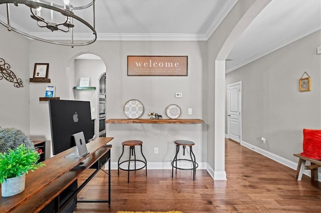 kitchen with crown molding, hardwood / wood-style floors, a breakfast bar area, and a notable chandelier