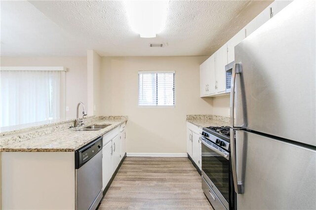 1841 Northwick Pl, Lithonia, GA 30058 - kitchen with appliances with stainless steel finishes, a textured ceiling, sink, white cabinets, and light hardwood / wood-style floors