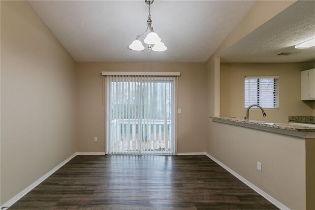 1841 Northwick Pl, Lithonia, GA 30058 - unfurnished dining area featuring a textured ceiling, sink, dark wood-type flooring, and an inviting chandelier