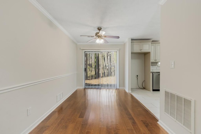 interior space featuring visible vents, light wood-style flooring, ceiling fan, and ornamental molding