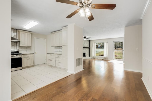 kitchen featuring visible vents, light wood-type flooring, open floor plan, gas range, and tasteful backsplash