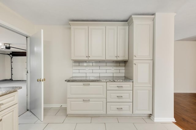 kitchen featuring decorative backsplash, light stone countertops, and light tile patterned flooring