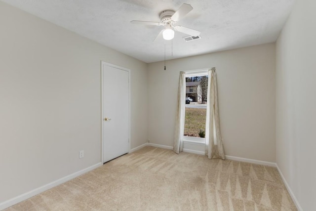 unfurnished room featuring carpet flooring, visible vents, baseboards, and ceiling fan