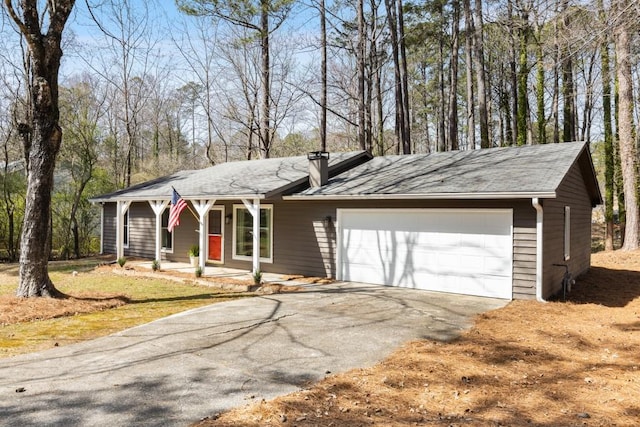 ranch-style house featuring covered porch, a garage, driveway, and a chimney