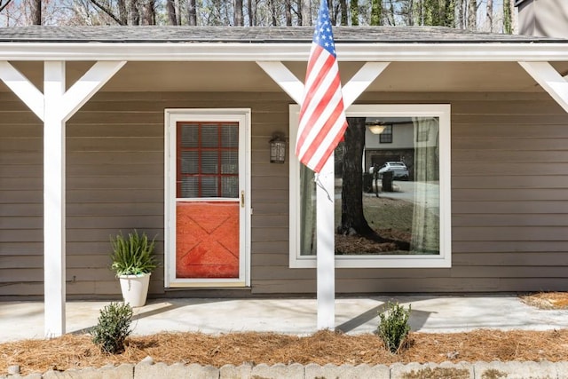 view of exterior entry with roof with shingles