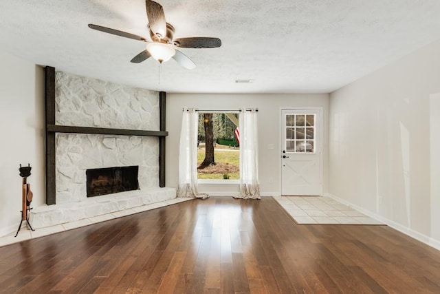 unfurnished living room with visible vents, a fireplace, ceiling fan, wood-type flooring, and a textured ceiling