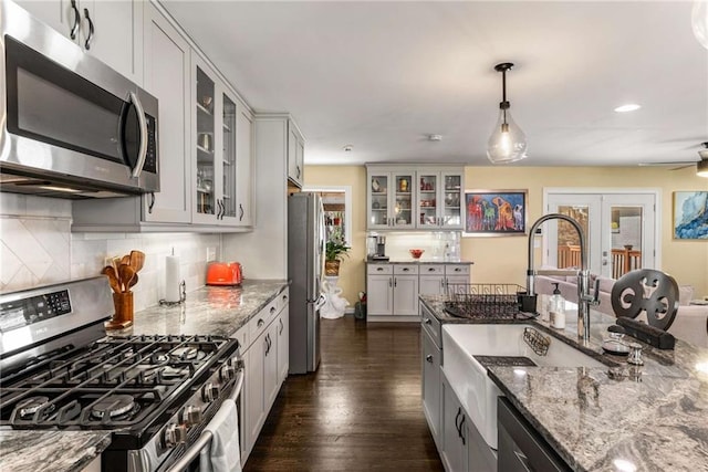 kitchen with light stone countertops, appliances with stainless steel finishes, a wealth of natural light, and french doors