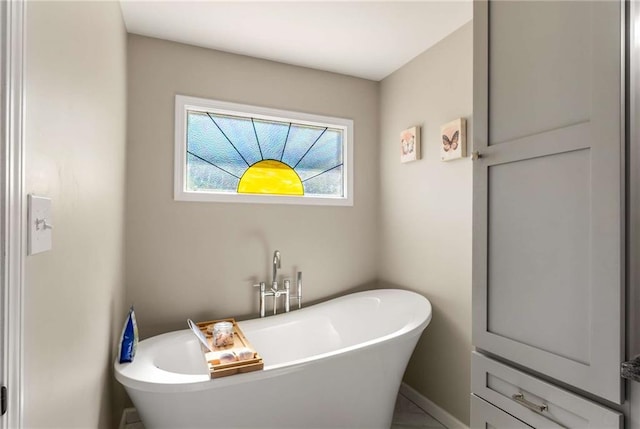 full bathroom with a freestanding bath and baseboards