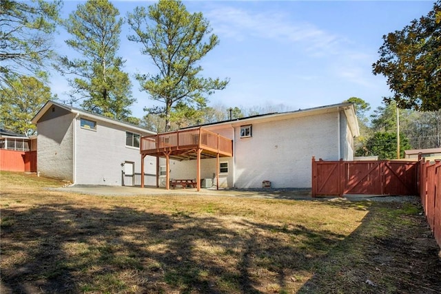 rear view of property featuring a deck, fence, a lawn, and a patio