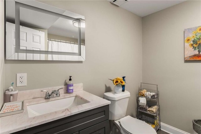 bathroom featuring toilet, baseboards, and vanity