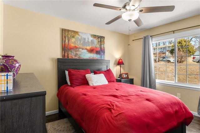 bedroom with ceiling fan, wood finished floors, and baseboards