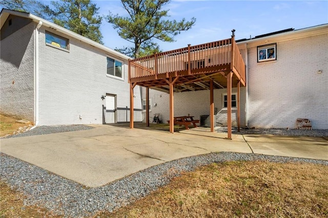 back of house featuring brick siding, a patio area, and a wooden deck