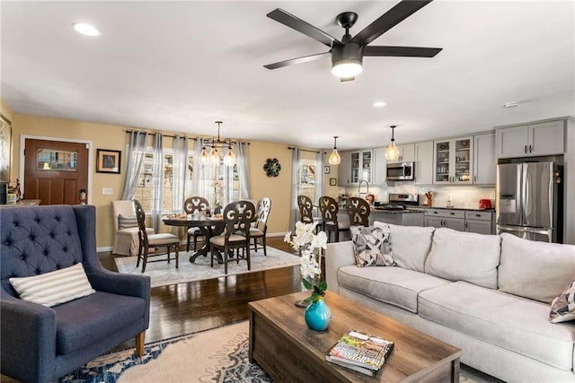 living room featuring recessed lighting, wood finished floors, baseboards, and ceiling fan with notable chandelier