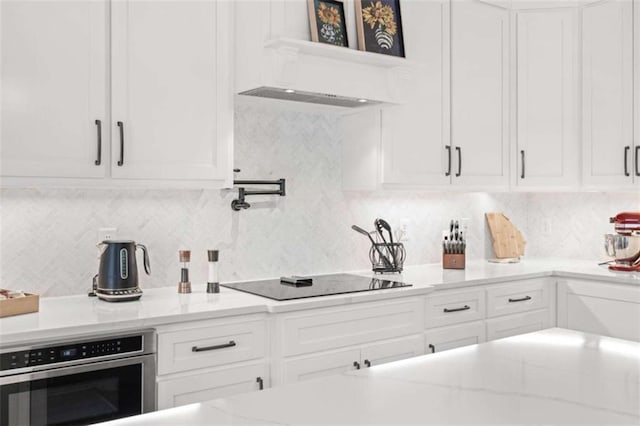 kitchen with white cabinets, tasteful backsplash, oven, and black electric cooktop