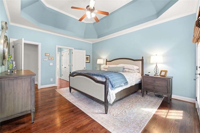 bedroom with dark hardwood / wood-style floors, ceiling fan, ornamental molding, and a tray ceiling