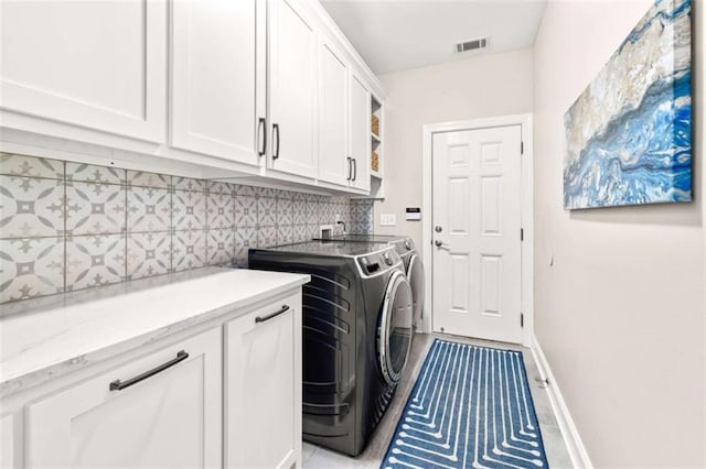 clothes washing area featuring cabinets and independent washer and dryer