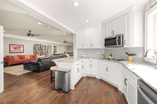 kitchen with stainless steel appliances, kitchen peninsula, sink, and white cabinets