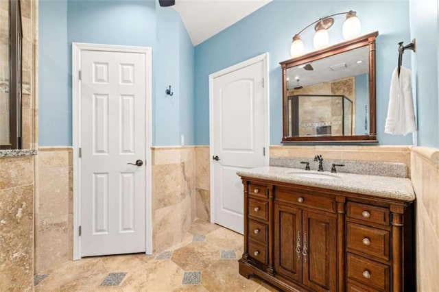 bathroom featuring tile walls, vanity, and a shower with shower door