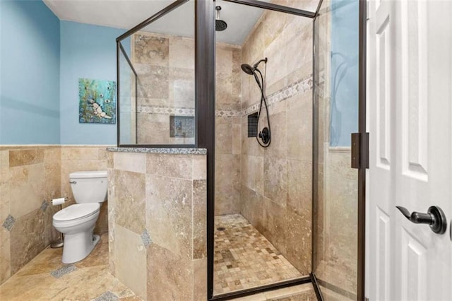 bathroom featuring tile walls, a shower with shower door, and toilet