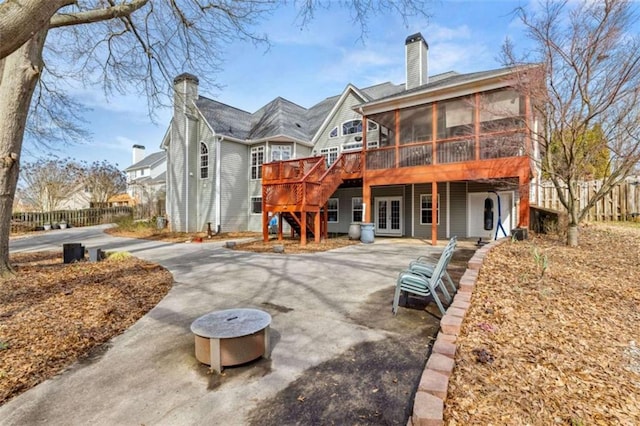 back of house with a wooden deck, an outdoor fire pit, a patio, and a sunroom