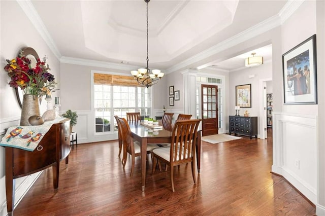 dining space featuring dark hardwood / wood-style flooring, crown molding, a raised ceiling, and an inviting chandelier