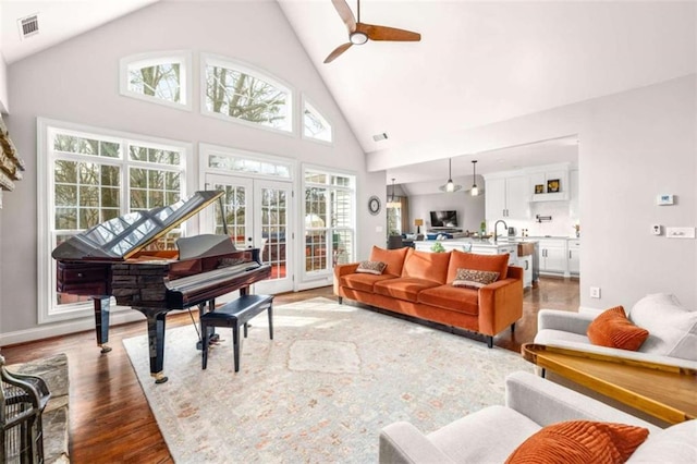 living room featuring ceiling fan, high vaulted ceiling, light wood-type flooring, and french doors