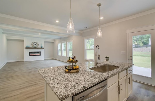 kitchen with light wood-style flooring, stainless steel dishwasher, ornamental molding, a glass covered fireplace, and a sink