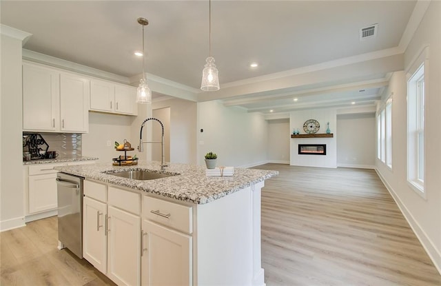 kitchen featuring light wood-style flooring, visible vents, a sink, and a glass covered fireplace