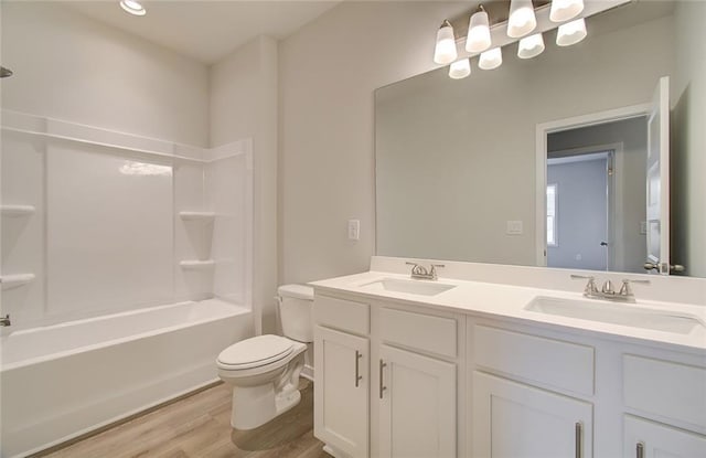 full bathroom featuring double vanity, a sink, toilet, and wood finished floors