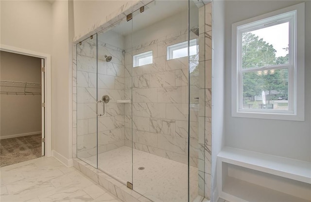 full bathroom with marble finish floor, a stall shower, a walk in closet, and a healthy amount of sunlight